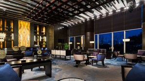 A modern lounge area with sofas, tables, and a large window offering a view of the night sky. - Wanda Realm Wuhu (Wuhu)