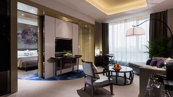Una habitación de hotel moderna con cama, escritorio, televisor, mesa redonda de comedor y sofá.