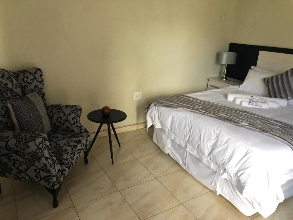 A hotel room with a bed, a chair, and a small table.