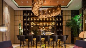A bar area with multiple seating options, a central bar counter, and a decorative ceiling piece. - Wanda Realm Jining (Jining)