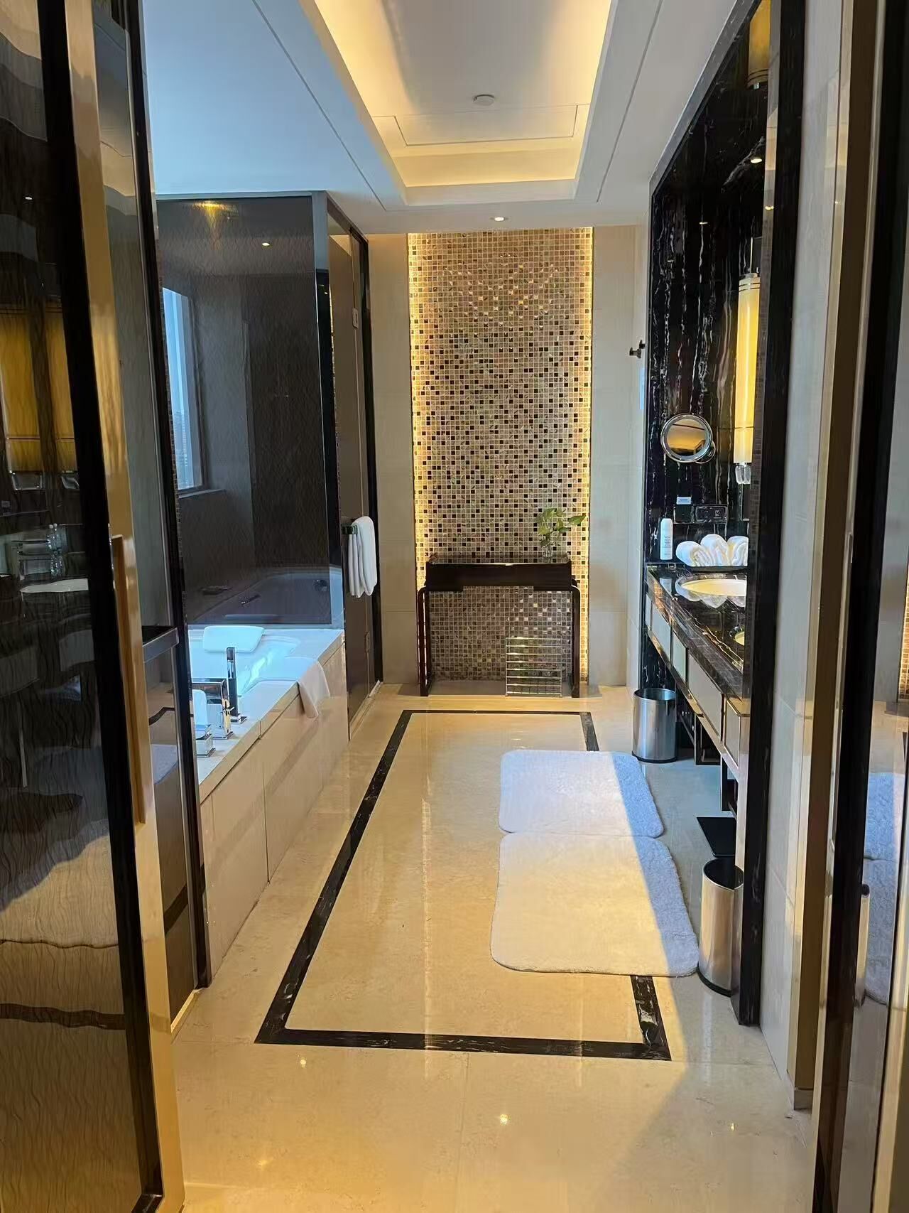 Un baño moderno con un espejo grande, una bañera y un revestimiento de azulejos.