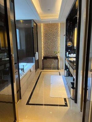 A modern bathroom with a large mirror, a bathtub, and a tiled wall.