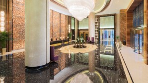 A spacious lobby with a central water feature, large columns, and a modern chandelier. - Wanda Realm Jining (Jining)