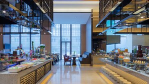 A modern hotel lobby with a long reception desk, seating area, and a view of the city through large windows. - Wanda Realm Jining (Jining)