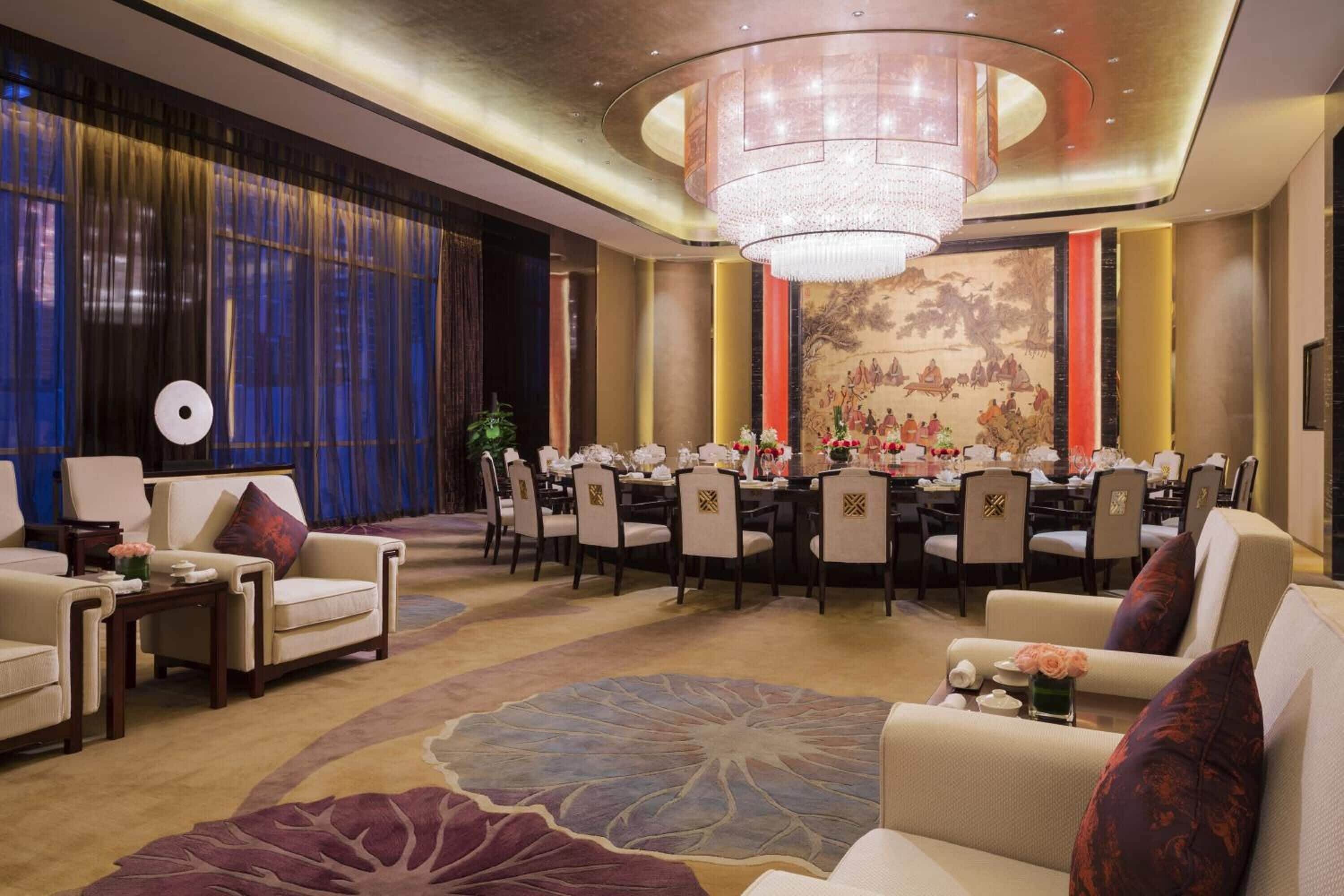 A formal dining room with a chandelier, round tables, and chairs.