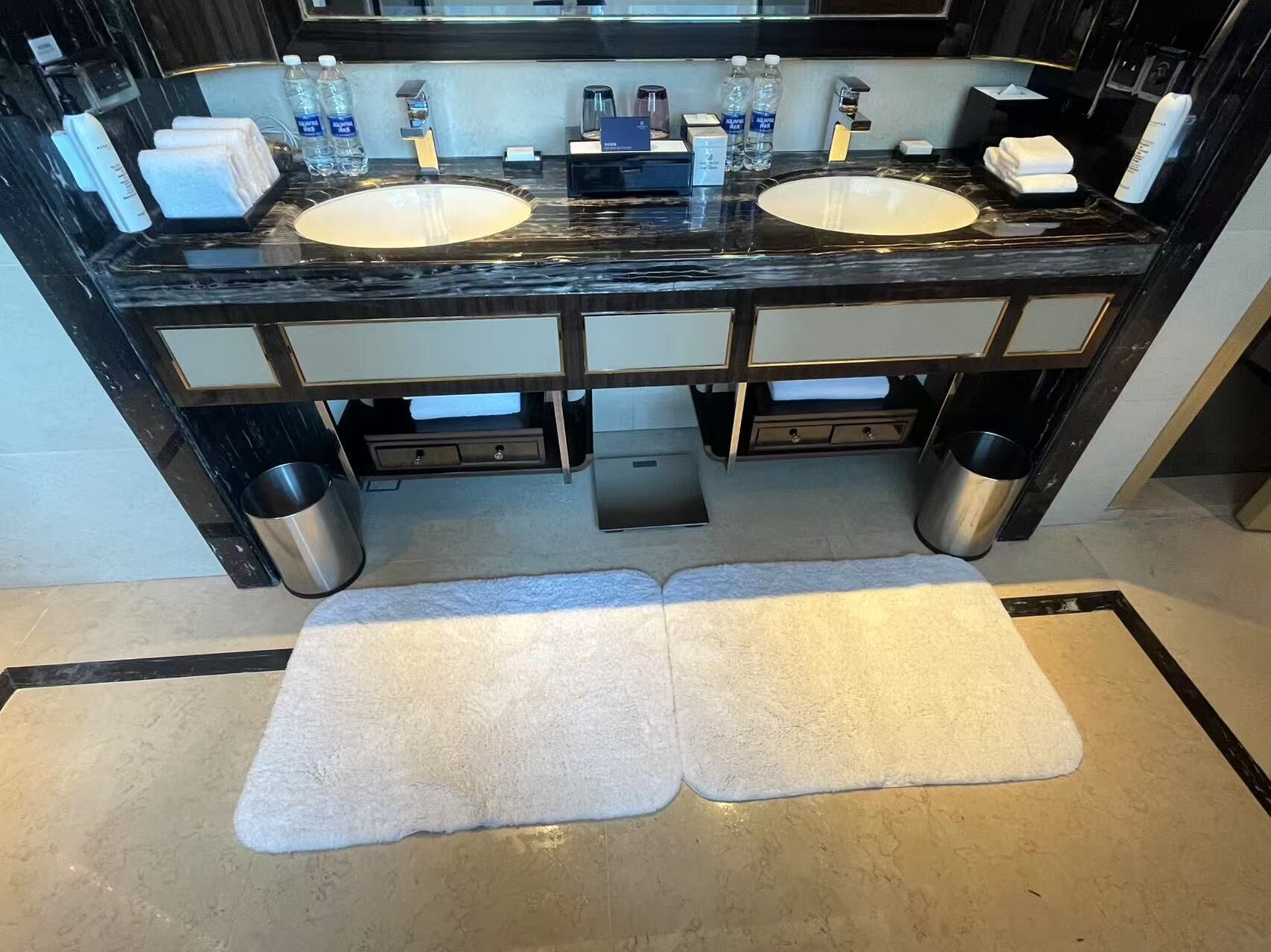 A modern bathroom with two sinks, a mirror, and a towel rack.