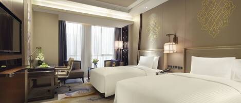 A hotel room with two beds, a desk, a chair, a TV, and a decorative wall piece.