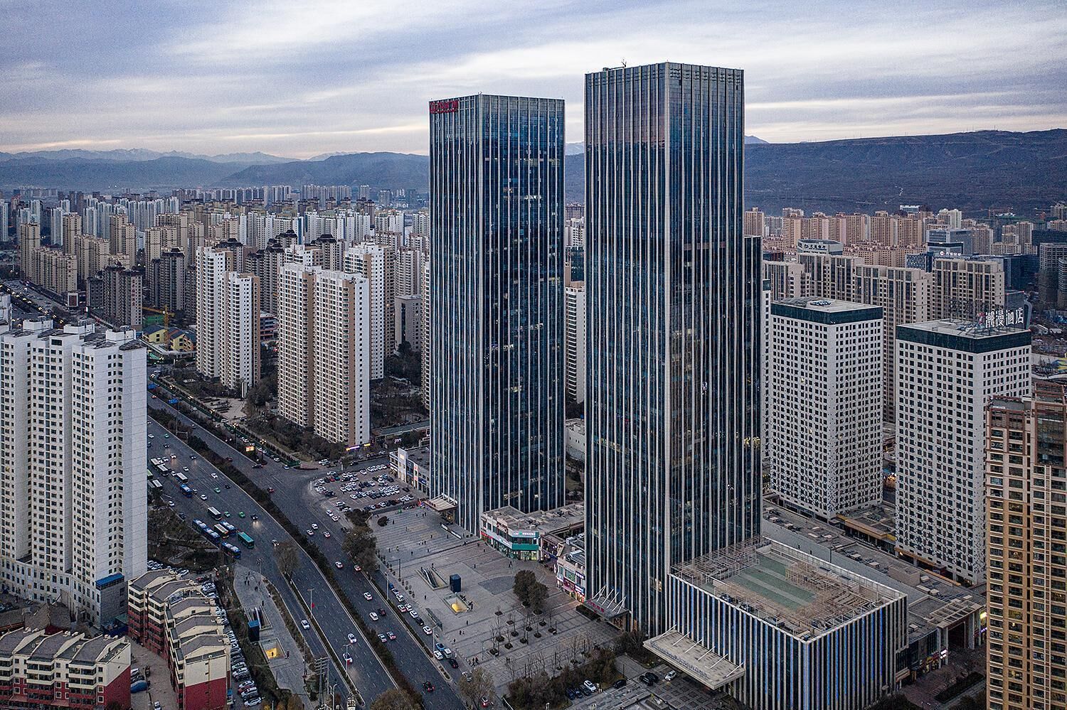 Un immeuble de grande hauteur doté d’une façade moderne en verre, entouré d’autres immeubles de grande hauteur dans un environnement urbain.