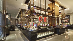 A modern hotel lobby with a central buffet area, seating arrangements, and decorative elements.