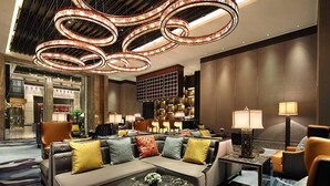 A modern lobby with a sectional sofa, a coffee table, and a chandelier. - Wanda Vista Xining (Xining)