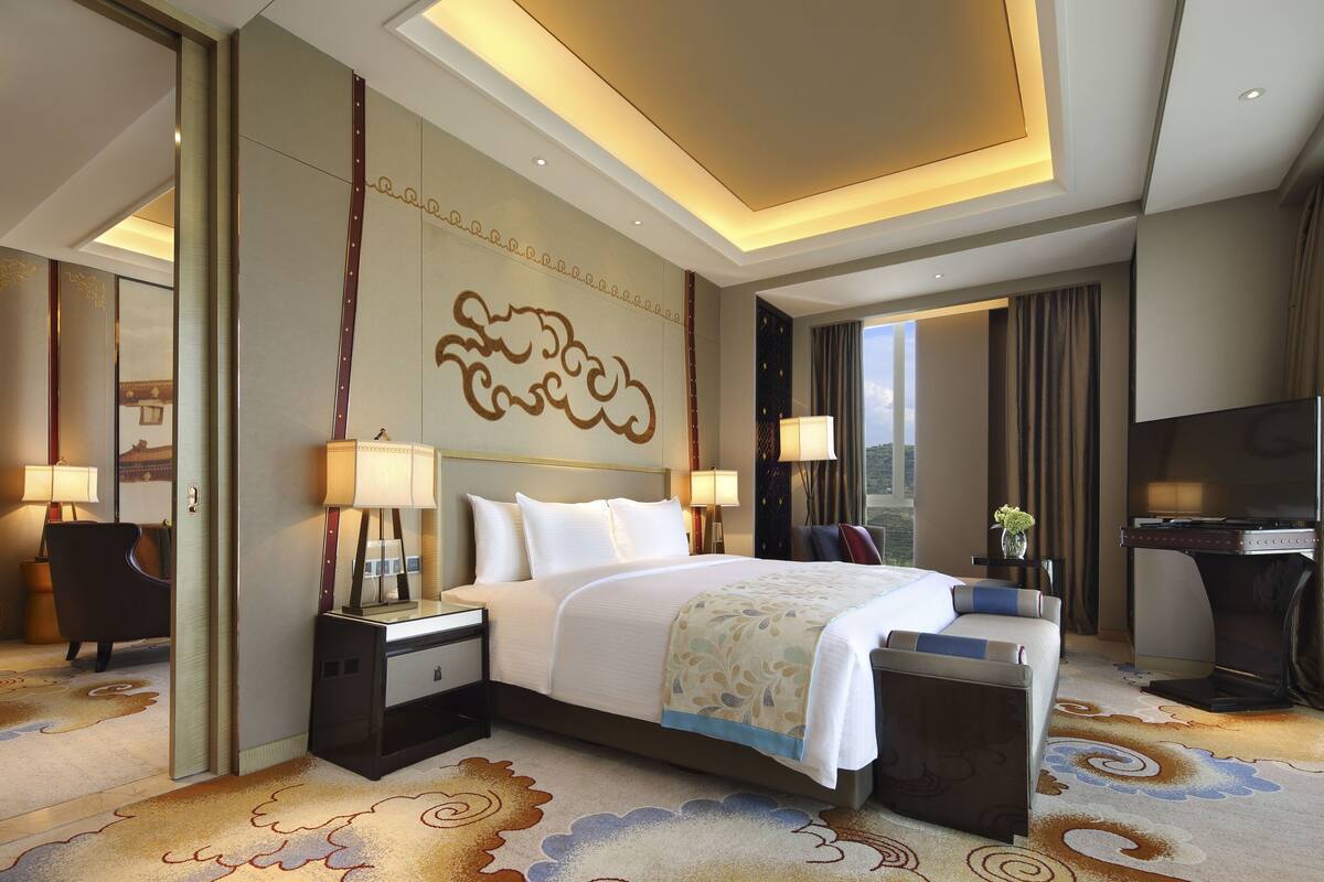 Una habitación de hotel con una cama grande, mesitas de noche, un escritorio y un televisor.