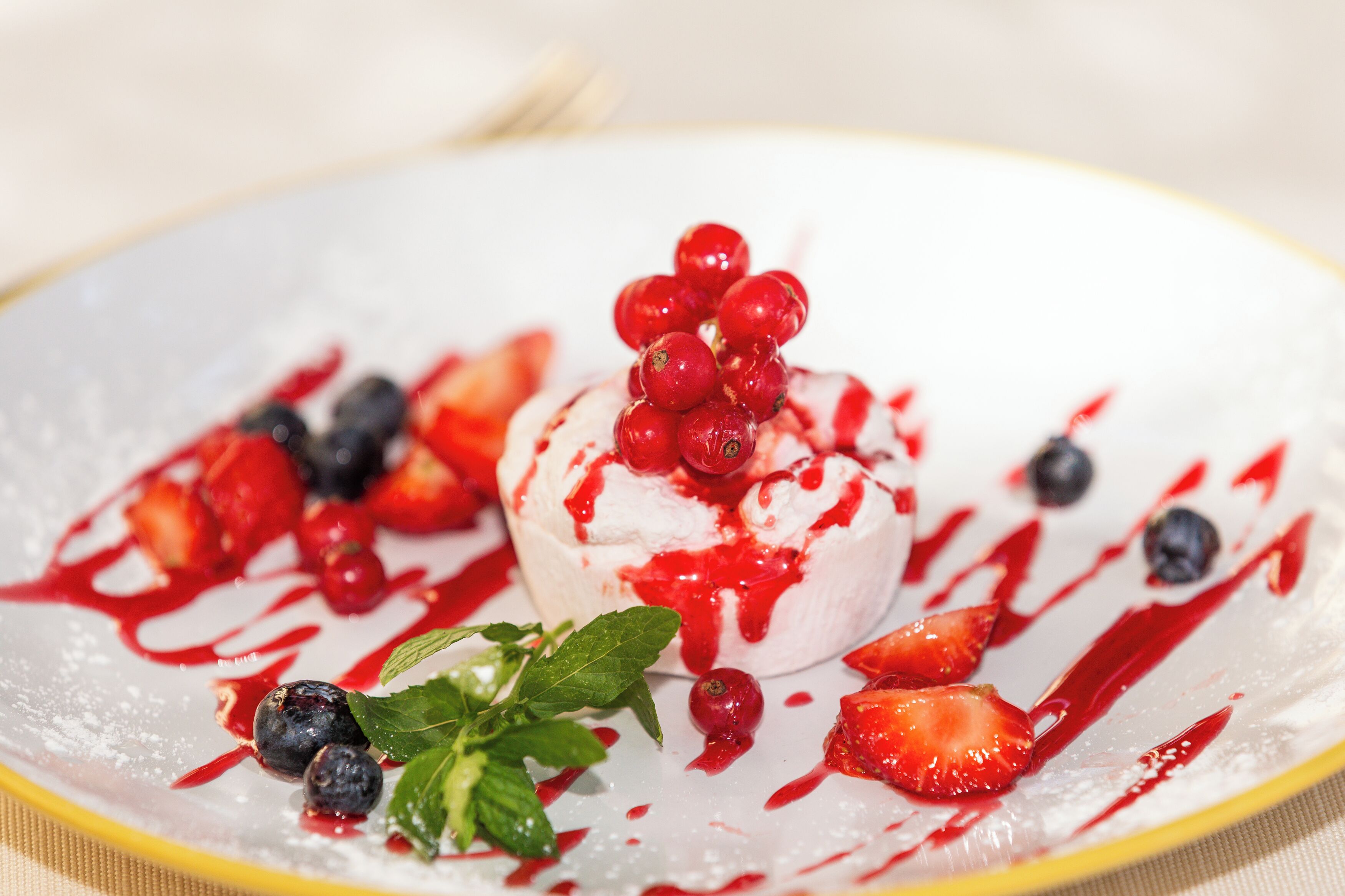 Sobremesa com frutas vermelhas e chantilly em um prato.