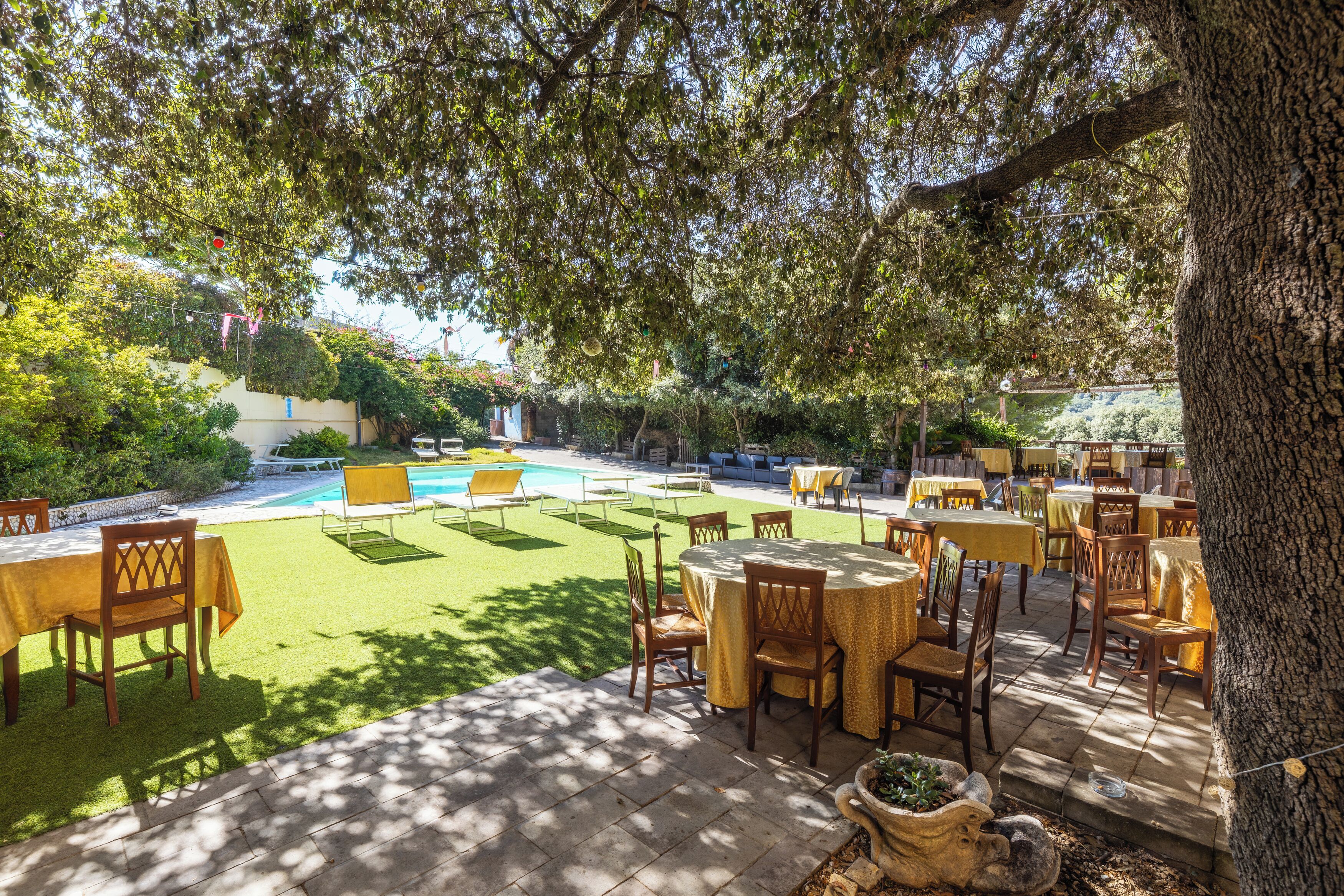 Ein Außenbereich mit Terrassentischen und -stühlen, einem Swimmingpool und einer Rasenfläche.