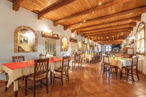 Un restaurante con vigas de madera y suelos de baldosas, con varias mesas y sillas.