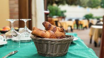 Een rieten mand gevuld met croissants op een tafel met een groene tafelkleed.