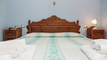 Un letto rifatto con cura, una coperta con motivo floreale, due comodini con lampade e una testiera in legno.