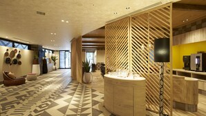 Un hall espacioso con suelo de diseño geométrico, una recepción y una máquina de café.