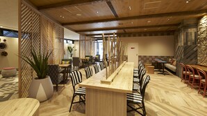 Un comedor amplio con una larga mesa de madera, sillas a rayas y una planta en maceta.