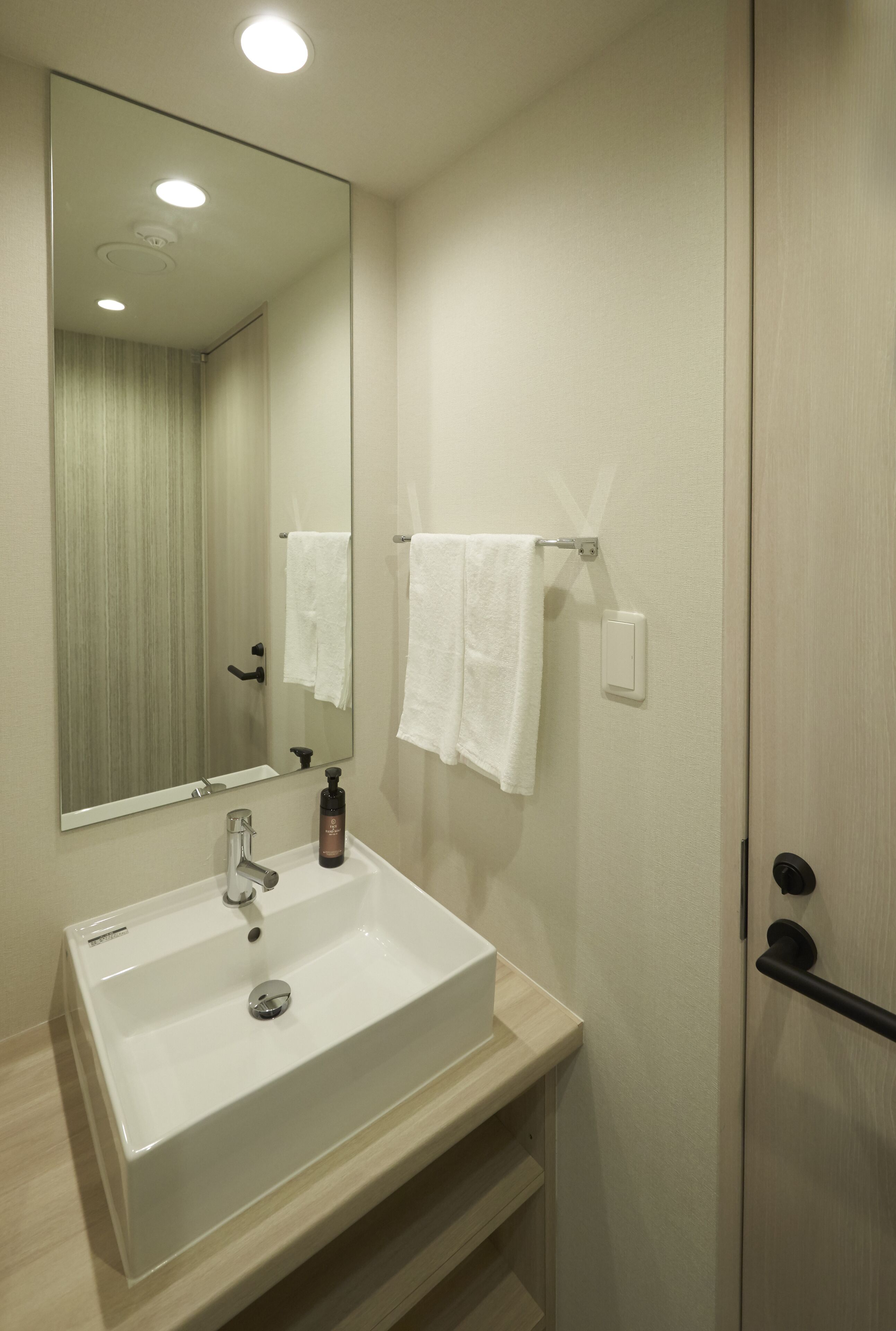 A bathroom with a white sink, a mirror, and two white towels hanging on hooks.