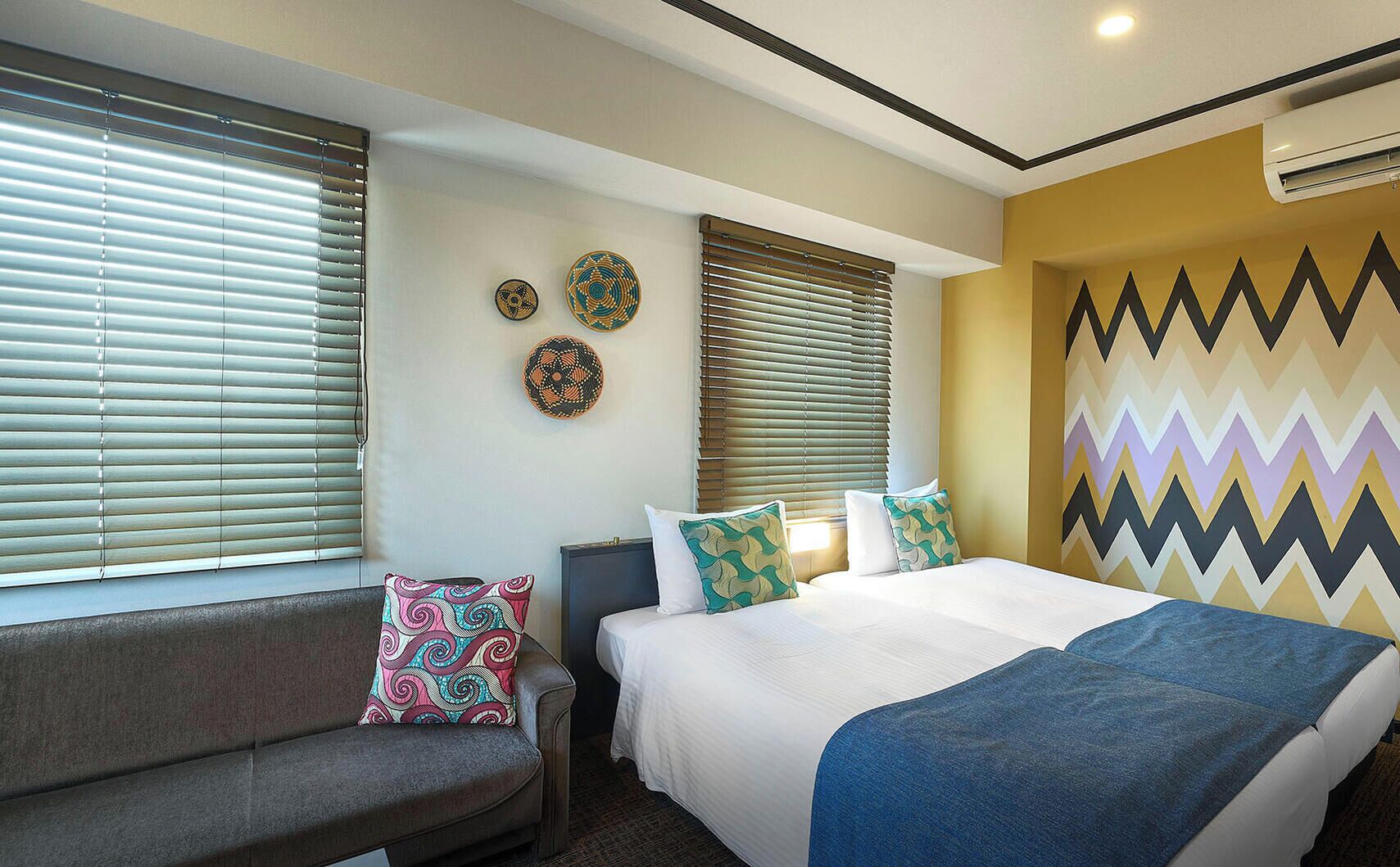 A hotel room with a bed, a sofa, and a wall with decorative plates.