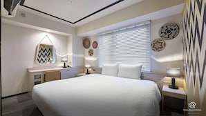 Habitación de hotel con una cama grande, mesitas de noche con lámparas, tocador con espejo y decoración en la pared.