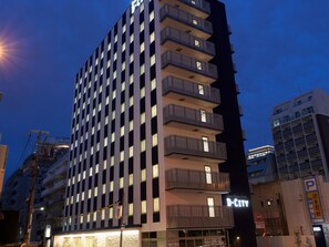 Een hoog hotel met meerdere balkons en een bordje waarop staat 'D-City hotel'.