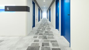 Een hotelgang met blauwe deuren, een vloerbedekking en een bordje met het nummer 6.
