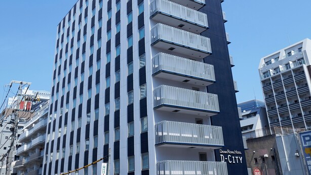 Een hoog gebouw met meerdere balkons, een bord met de tekst Daiwa Royal Hotel en de aanduiding 'D-CITY' op de gevel.