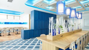 Een modern restaurant met blauw-wit decor, houten meubels en hangende吊灯.