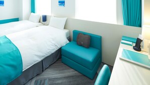Een hotelkamer met twee bedden, een kleine zithoek en een bureau met een lamp.