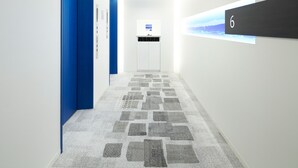 Een moderne hal met blauwe deuren, een digitaal informatiebord en een vloerbedekking.