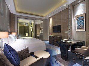 Ein Hotelzimmer mit einem großen Bett, einem Schreibtisch, einem Stuhl, einem Fernseher und einem Badezimmer.