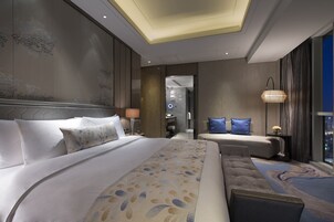 Una habitación de hotel moderna con una cama grande, un sofá y vistas a la ciudad.