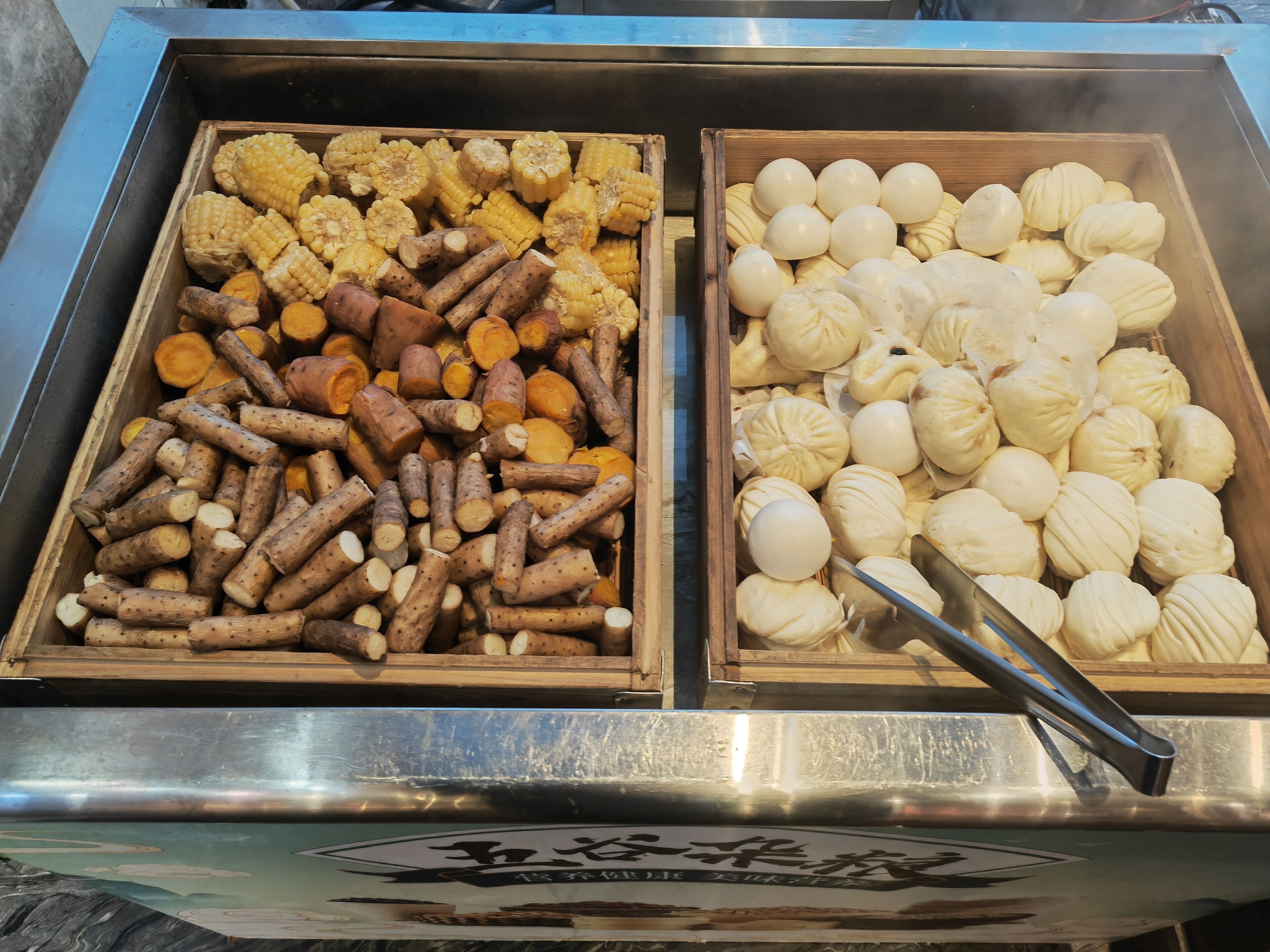 Una presentación de comida con diversos elementos, como mazorcas de maíz, batatas y albóndigas blancas.