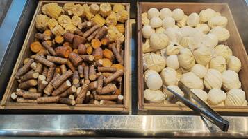 Una presentación de comida con diversos elementos, como mazorcas de maíz, batatas y albóndigas blancas.