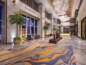 A spacious lobby with a patterned carpet, seating areas, and large windows. - Pullman Yantai Center (Yantai)