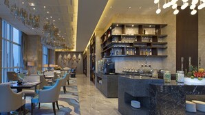 A modern hotel lobby with a dining area, a bar, and a reception desk. - Pullman Yantai Center (Yantai)