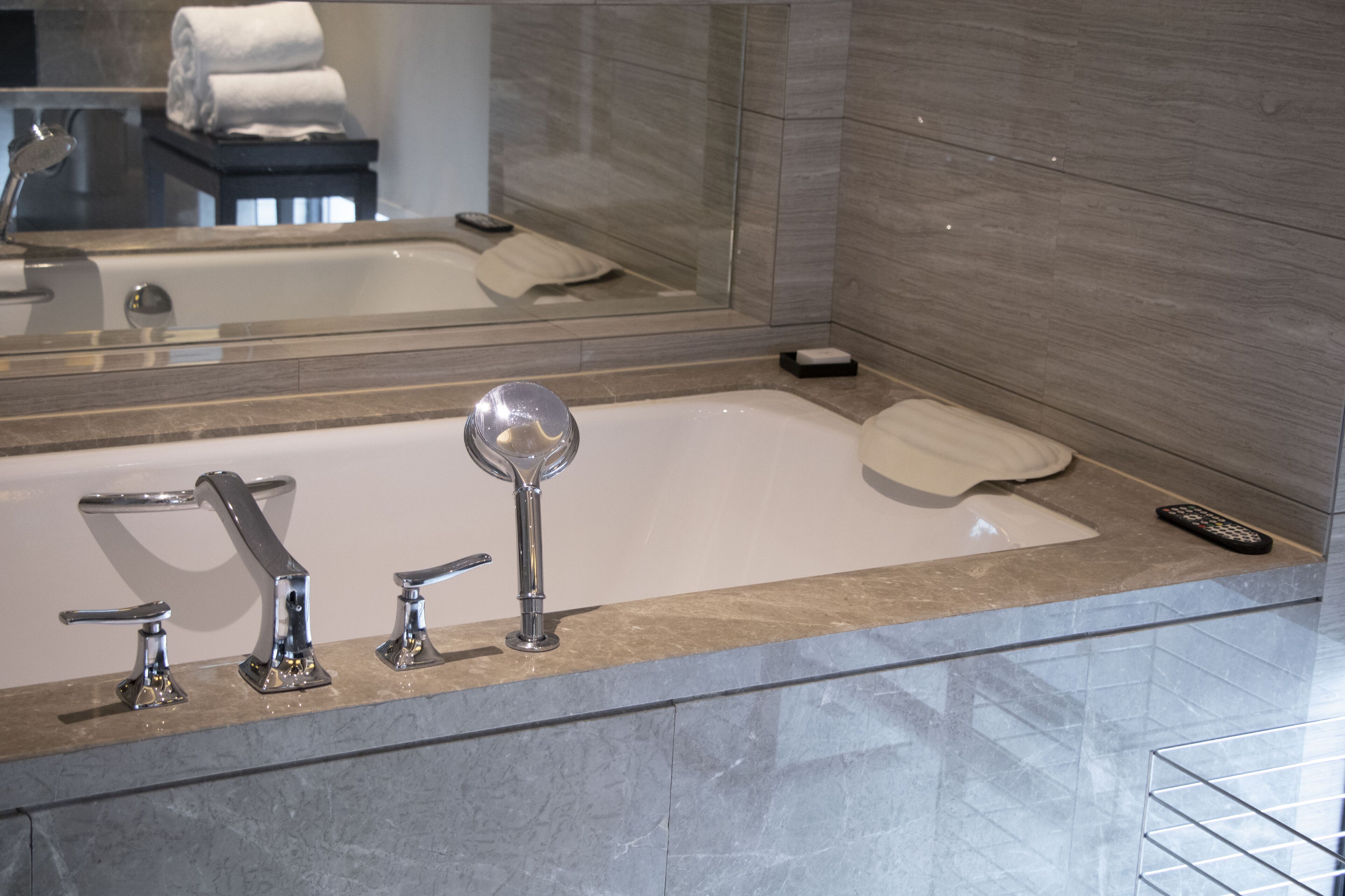 Une salle de bain moderne dotée d’une grande baignoire, d’une douchette et d’un appareil de massage portatif.