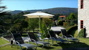 Un patio con sillones de descanso y una mesa, con vistas a un paisaje montañoso con aerogeneradores.