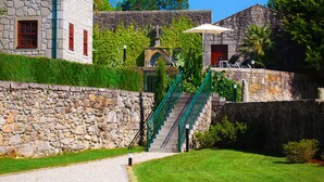 Un edificio de piedra con una escalera que conduce a un espacio cubierto con sillas y una sombrilla.