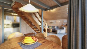 Un intérieur en bois comprenant une table à manger dressée pour un repas, un escalier et un coin salon avec un canapé et une table basse.