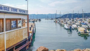 Un port de plaisance avec des bateaux amarrés, un bâtiment sur lequel on peut lire l’inscription « 5 Terre Portofino », et des montagnes en arrière-plan.