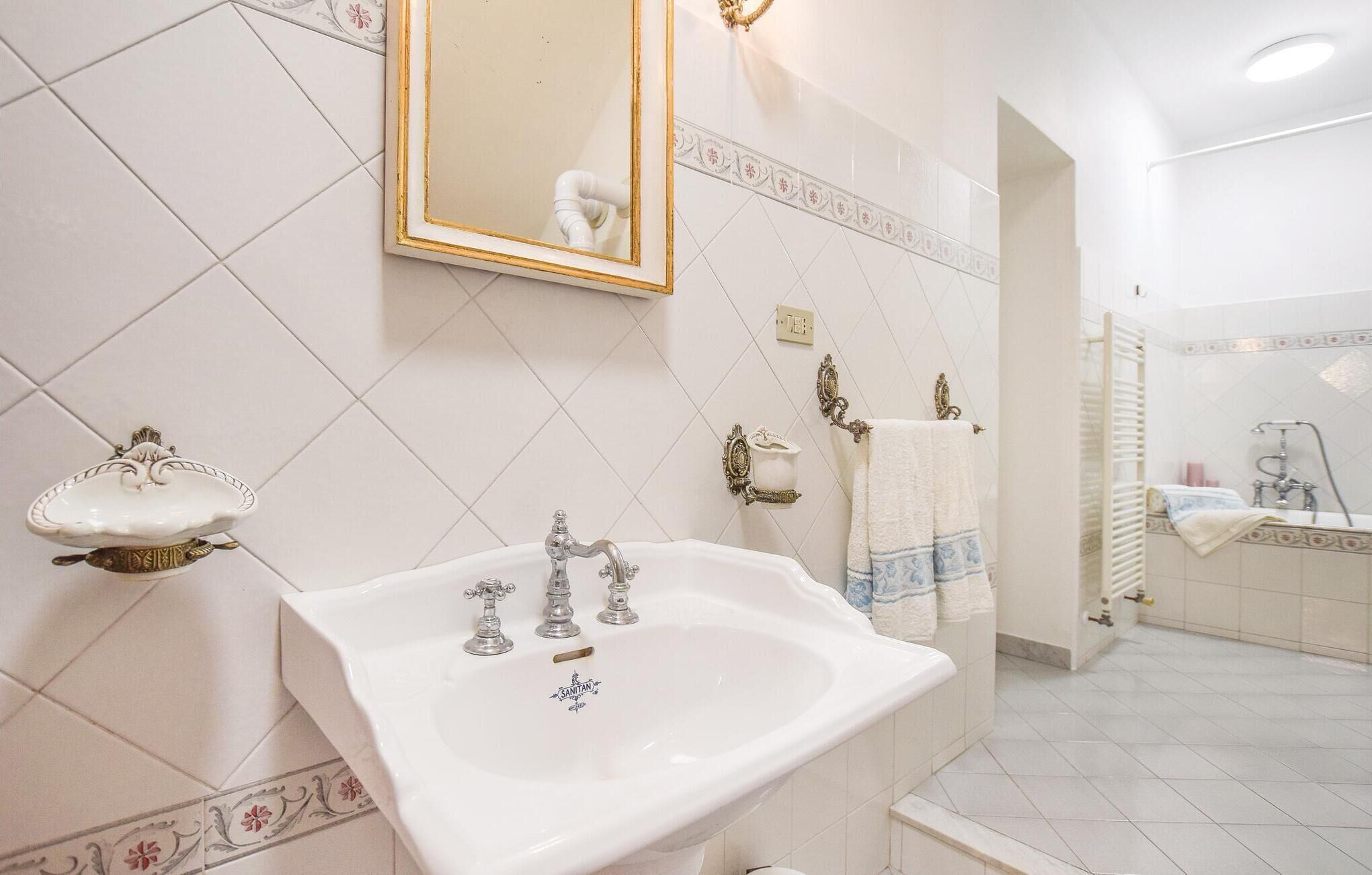 A bathroom with a white sink, two faucets, a mirror with a gold frame, and a decorative soap dish.