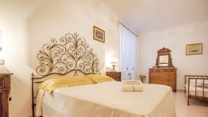 Une chambre à coucher bien rangée, avec un grand lit, une table de chevet avec une lampe, une commode et un miroir.