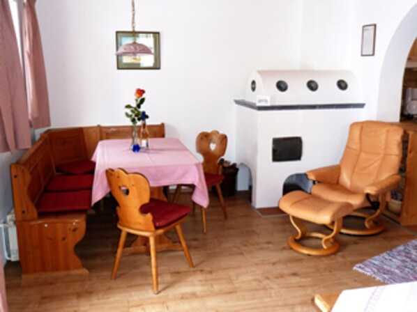 Una habitación acogedora con un banco de madera, una mesa con mantel rosa y un sillón mecededor.