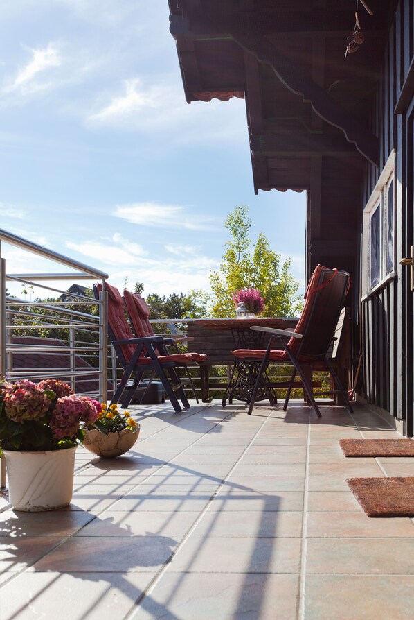A patio with a table and chairs, potted plants, and a view of the sky. - Apartment with a large terrace (Insel Hiddensee)