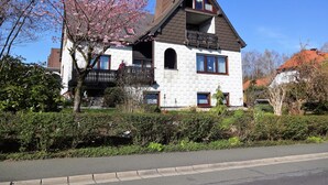 Une maison à deux étages avec un balcon, une cheminée et un jardin à l’avant.