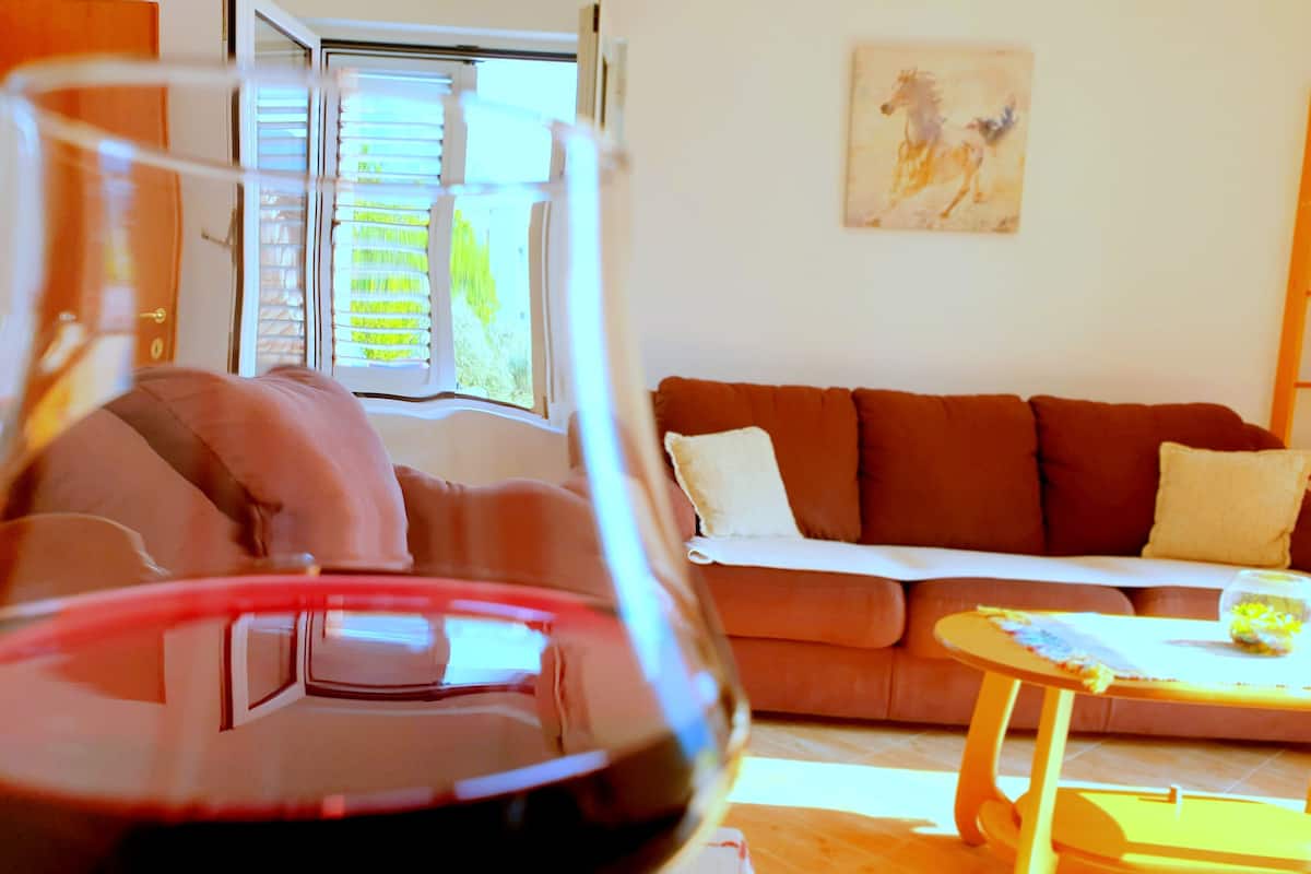 Uma sala de estar com um sofá, uma mesa de centro e um copo de vinho tinto.