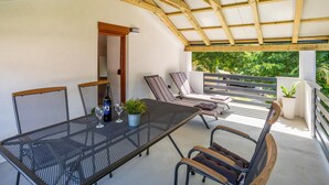 Une terrasse extérieure avec une table en métal, des chaises et une bouteille de vin PlayaC.