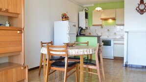 A compact kitchen with a dining table, chairs, and a refrigerator. - 2-bedroom apartment, sleeps 6, air conditioning and parking in Banyuls (Banyuls-sur-Mer)